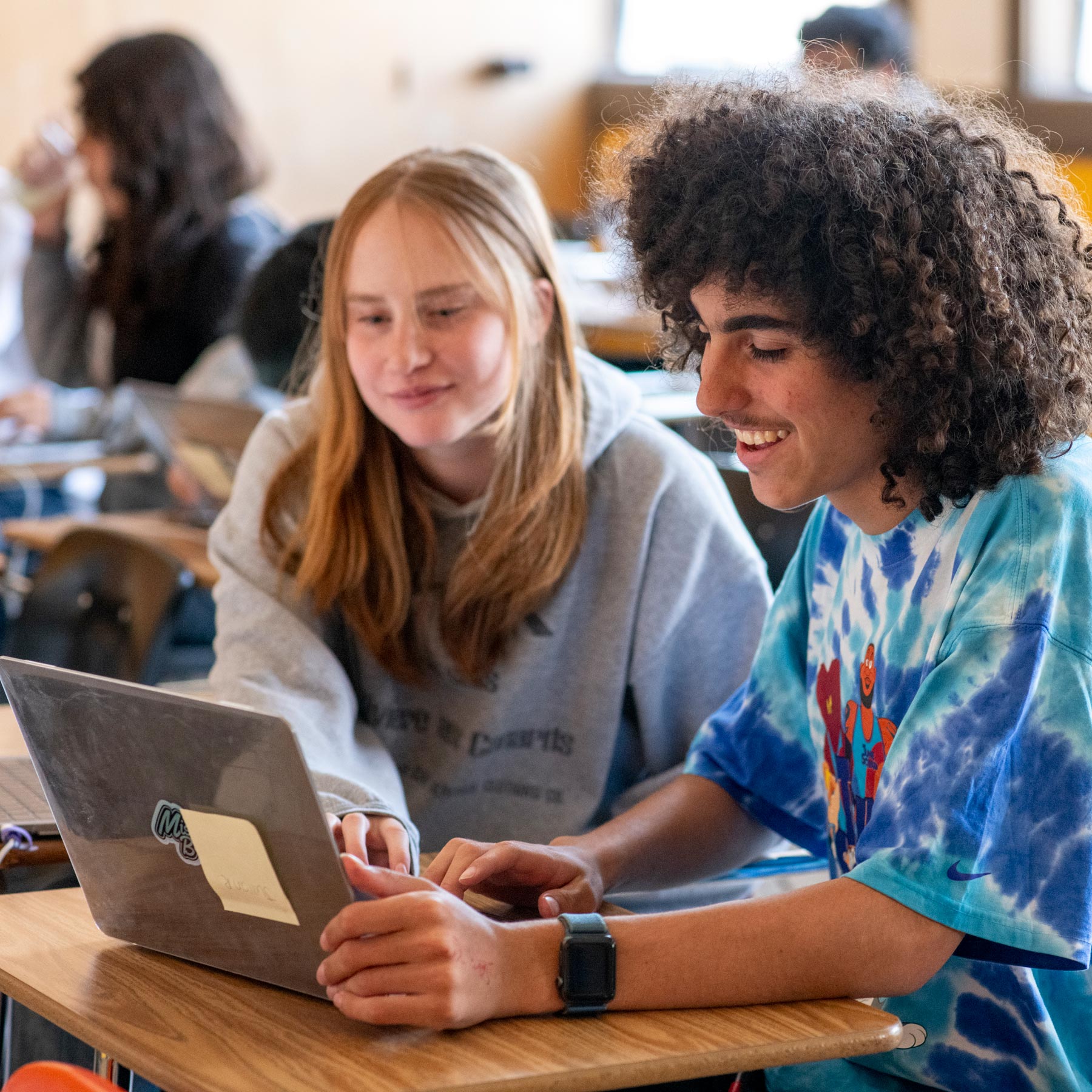 Two Mission Bit students smiling while coding together during a Mission Bit coding course.