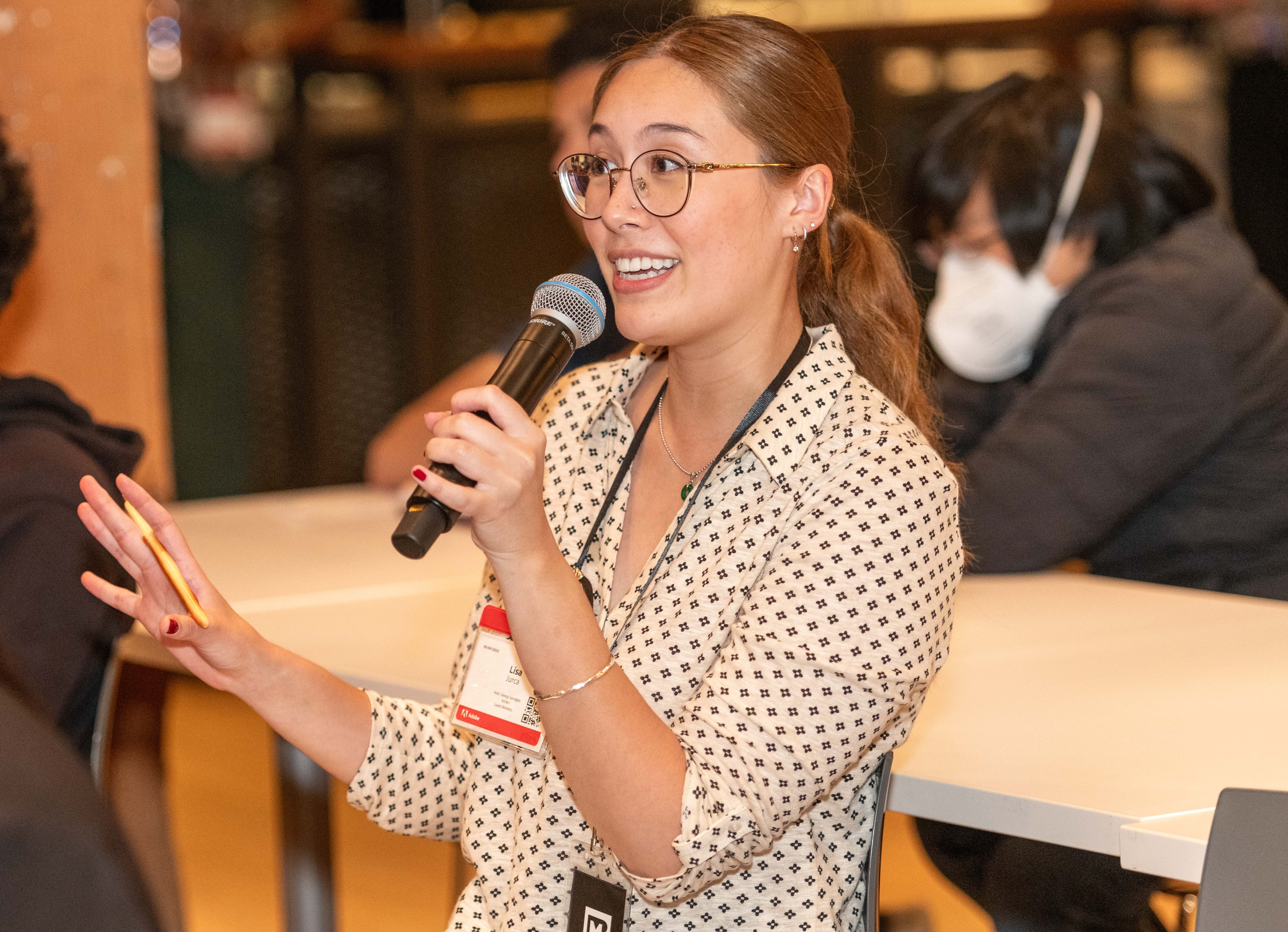 Mission Bit instructor speaking into a microphone during Demo Day, an event where students present their computer science projects.