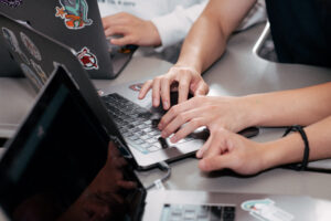Close-up of high school students coding on laptops during a Mission Bit class, working hands-on to build projects and experiment with programming and AI tools