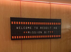 A display inside Reddit’s office reads “Welcome to Reddit HQ” and “Mission Bit.”